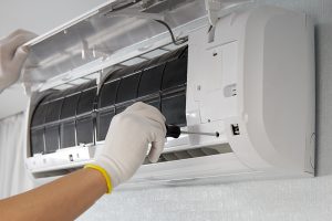Hands of a male technician repairing an indoor air conditioner using a screwdriver. 