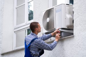 A technician repairing an AC unit outside a home.