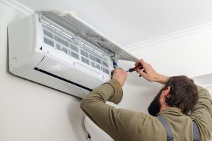 Technician working on an air conditioner. Modern air conditioner during the installation process. Worker installs indoor unit of the air conditioner.