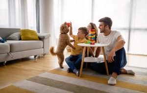 Young family playing in home with dog